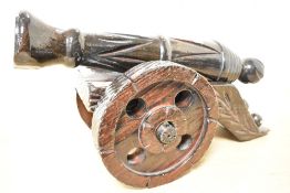 A large decorative 20th-century handcarved wooden cannon on wheels, with carved decoration along the