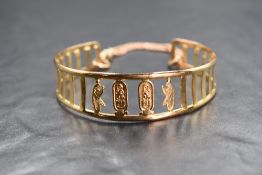 An Egyptian 18ct gold cuff bracelet, having pierced panels with central cartouches, Egyptian 18ct