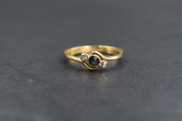 An 18ct gold sapphire and diamond set ring, the central round cut sapphire flanked by two old cut