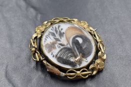 A large yellow metal mourning hair brooch, the central panel having decorative hair scrolls in an