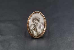 A yellow metal presumed gold portrait ring, the oval panel depicting a maiden holding a cross bow,