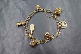 A 9ct gold double link bracelet having six 9ct gold charms and one yellow metal charm, presumed