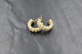 A pair of yellow metal pearl set hoop earrings, the two of rows cultured pearls on an openwork