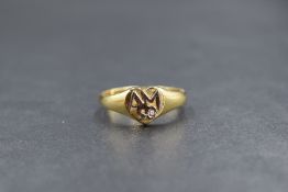 An 18ct gold signet ring bearing appliqu? monogram AM 50 and small inset diamond to heart shield