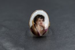A 12ct gold portrait ring, the ceramic oval panel depicting a young gentleman in a bezel setting,