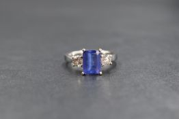 An 18ct white gold tanzanite and diamond three stone ring, the central emerald cut tanzanite