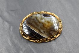 A large oval brown striped agate brooch in a decorative pinchbeck mount