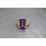 A 9ct gold amethyst ring having a large emerald cut stone in a raised basket mount to pierced