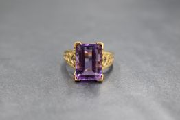 A 9ct gold amethyst ring having a large emerald cut stone in a raised basket mount to pierced