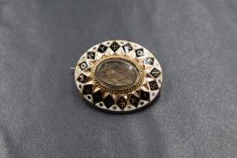 A rose metal enamelled mourning brooch, of oval form having a central oval panel containing