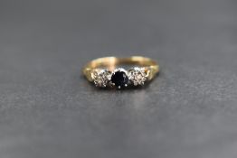 A 9ct gold sapphire & diamond ring having a small claw set sapphire flanked by two small illusion