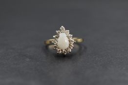 A 9ct gold opal and cubic zirconnia pear cluster ring having a central cabochon opal within a