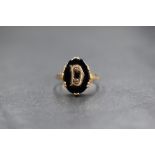 A 9ct gold mourning ring, the oval onyx panel having a 'D' initial to the centre, marked 375, ring