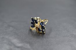 A 9ct gold sapphire ring having nine marquise cut sapphires in a floral design surrounding a small