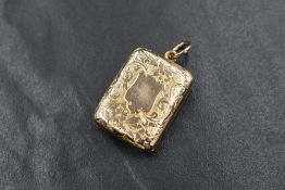 A yellow metal presumed gold locket, of rectangular form having scroll decoration and a vacant