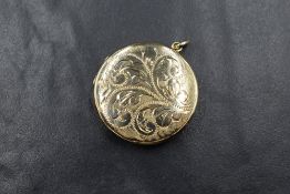 A 9ct gold locket pendant, of circular form having scroll decoration to the front, marked 375, 3cm