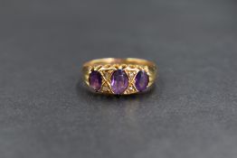 An 18ct gold amethyst and diamond set three stone ring, the three oval graduated amethysts