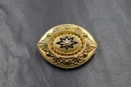 A yellow metal mourning brooch having a central seed pearl in a blue star setting with yellow