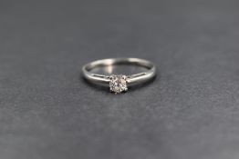 A white metal diamond set solitaire ring, the round brilliant cut diamond in a four claw setting,