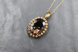 An oval smoky quartz cluster pendant in a 9ct claw set basket mount on a fine 9ct gold rope chain,