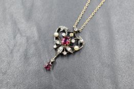 An Edwardian white metal ruby, diamond and pearl set pendant, the central oval cut ruby in a