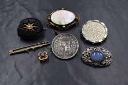 A group of six brooches, comprising a pearl set mourning brooch, two coin set brooches, a mother