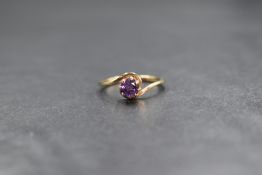 A 9ct gold amethyst set ring, the round cut amethyst in a cross over setting, marked 375, ring