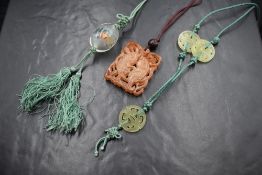 A Chinese carved orange jade style pendant depicting two fish within water, with a wooden bead on