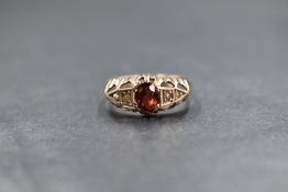 A yellow metal presumed gold garnet and pearl set ring, the central oval cut garnet flanked by two