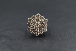 An 18ct white gold diamond set cluster ring, the nineteen round brilliant cut diamonds in a step