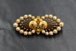 A high carat gold pearl set brooch, the central floral motif flanked by graduated pearl set