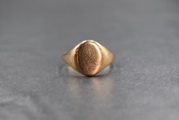 A yellow metal presumed gold signet ring, having an oval panel of plain form, unmarked, ring size S,