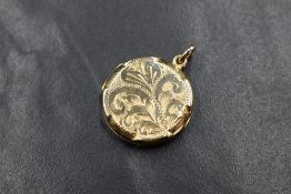 A 9ct gold locket, of circular form having scroll decoration to the front, marked 375, 4.4g