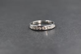 An 18ct white gold diamond set band, the eleven round brilliant cut diamonds in a channel setting,