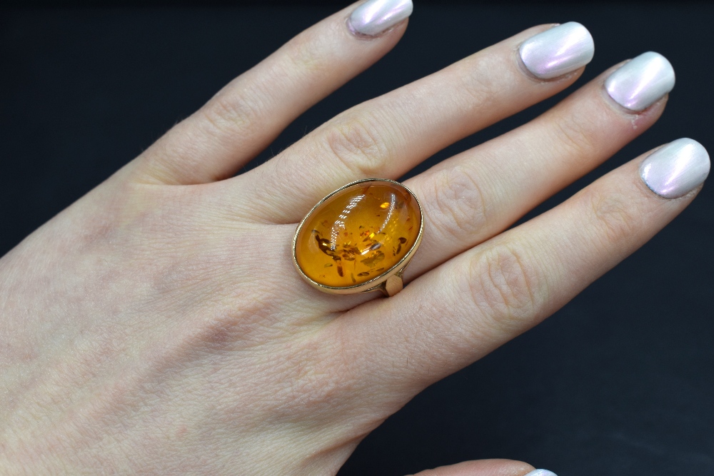 A 9ct gold amber set ring, the oval amber cabochon in a bezel setting having split shoulders, marked - Image 3 of 3
