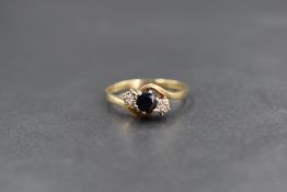 A 9ct gold sapphire and diamond three stone ring, the central round cut sapphire flanked by two