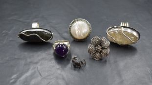 A group of six silver and white metal rings, comprising two artisan labradorite and rutile quartz