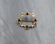 A 9ct gold oval garland brooch having four small garnets in floral surrounds, approx 3.7g