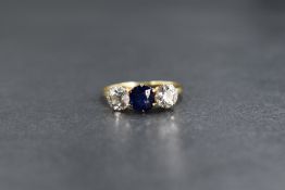 An 18ct gold sapphire and diamond set three stone ring, the central cushion cut sapphire measuring