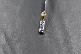 A small 18ct gold mounted ceylon sapphire pendant having four small princess cut stones in a channel