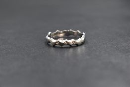 A platinum diamond set band, the wave motif band having three diamond chips, marked 950, ring size