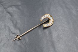 A yellow metal presumed gold enamelled opal and diamond set stick pin, the horseshoe set with