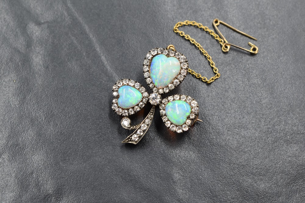 A yellow metal presumed gold opal and diamond set clover motif brooch, the three graduated opals