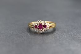 A 9ct gold ruby and diamond cluster ring having three small rubies within a surround of diamond