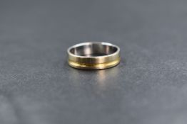 An 18ct gold two tone band, the white gold band having a yellow gold channel decoration, marked 750,