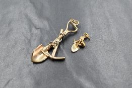 A 9ct gold mining pendant, having a shovel and pick wrapped in rope with a gold nugget, marked