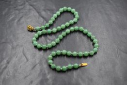 A knotted string of jade style beads of even form, having a silver gilt filigree box clasp, approx