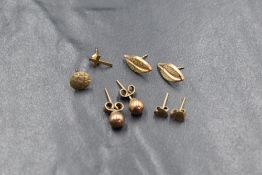 Three pairs of yellow metal earrings for pierced ears, including leaf and sphere, and two