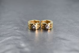 A pair of 18ct gold diamond set hoop earrings, the thick hoops having geometric engraving and a
