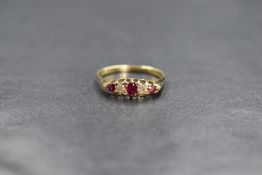 A yellow metal ruby & diamond ring having three small graduated rubies interspersed by two old cut